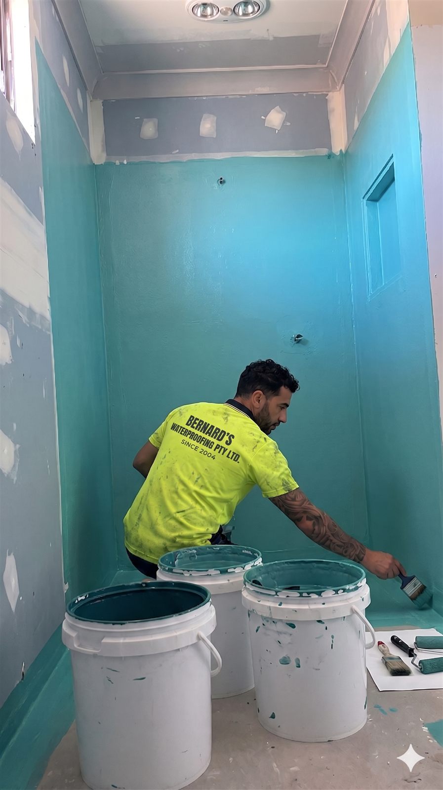 Bernard Waterproofing team member applying membrane to bathroom walls and floor
