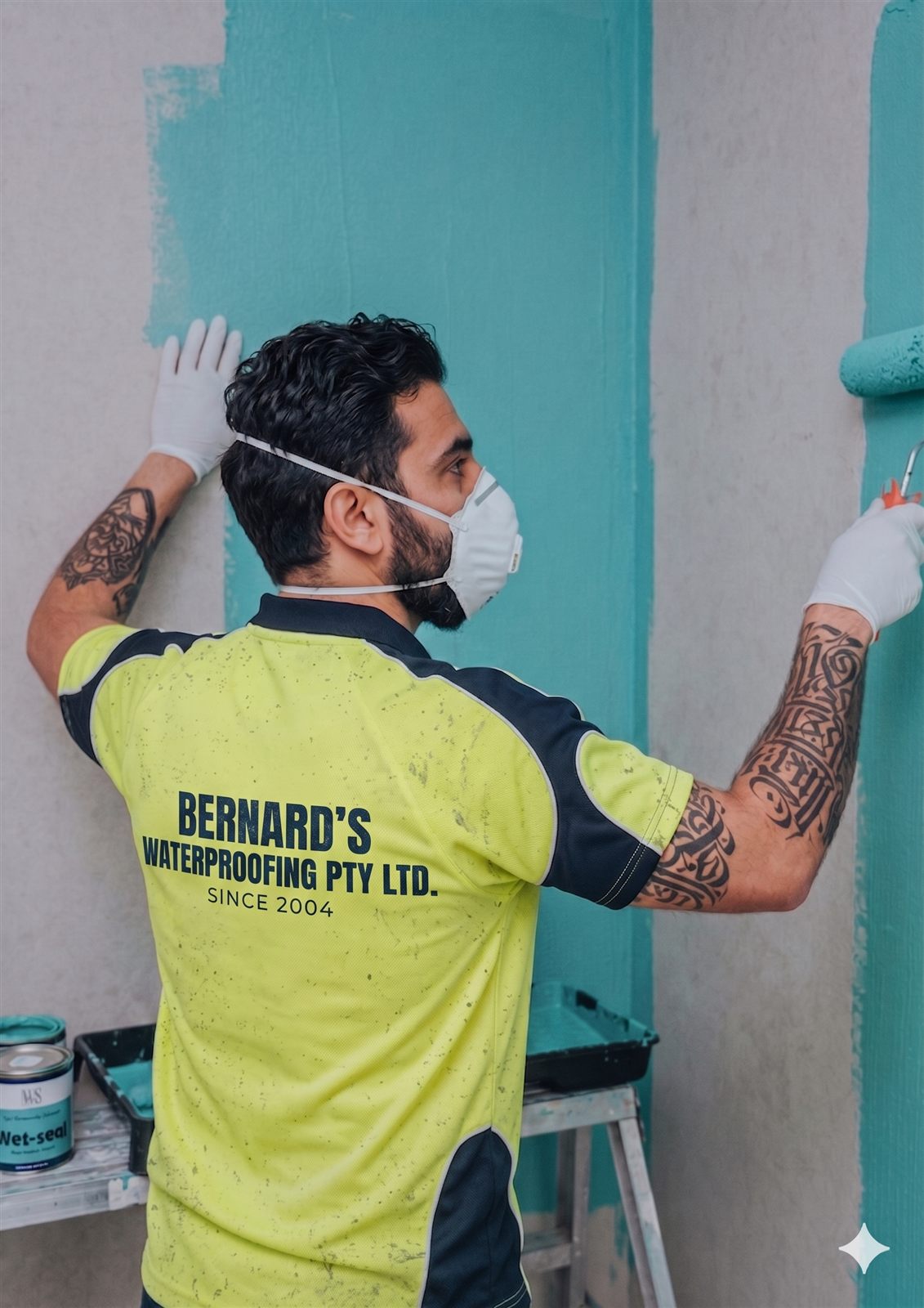 Bernard Waterproofing team member in branded uniform applying waterproofing membrane to an external wall
